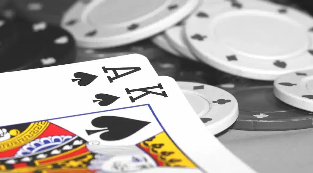 Ace and King of spades forming blackjack against a backdrop of casino chips.